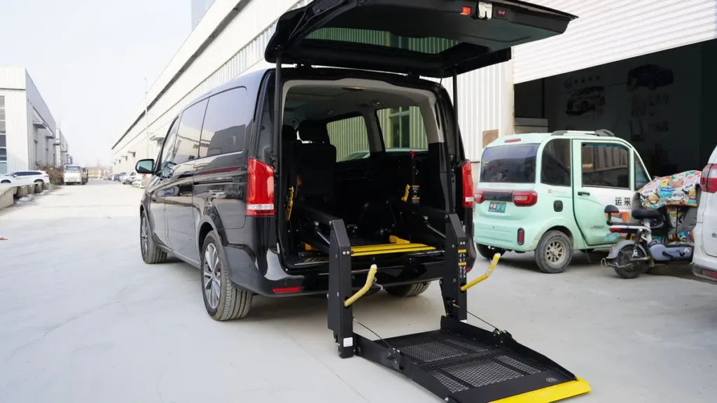 Dark van with its tailgate raised and a folding wheelchair lift platform lowered to the ground at the rear
