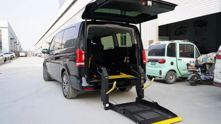 Dark van with its tailgate raised and a folding wheelchair lift platform lowered to the ground at the rear
