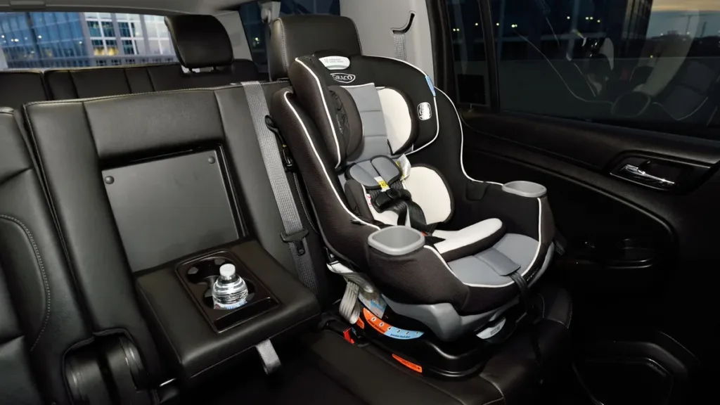 Empty convertible child car seat fitted on the rear passenger seat of a vehicle with dark upholstery