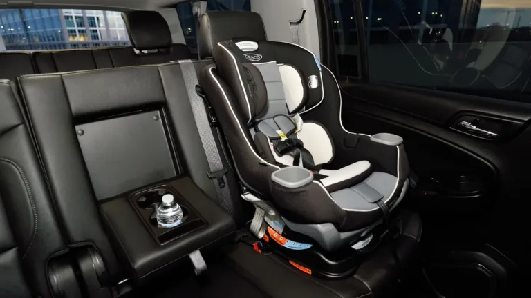 Empty convertible child car seat fitted on the rear passenger seat of a vehicle with dark upholstery