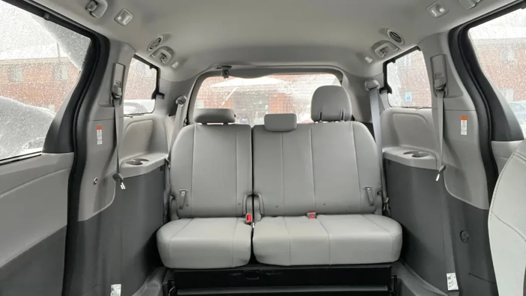 Interior of a people carrier with sliding doors open, showing grey leather seats and a rear bench row