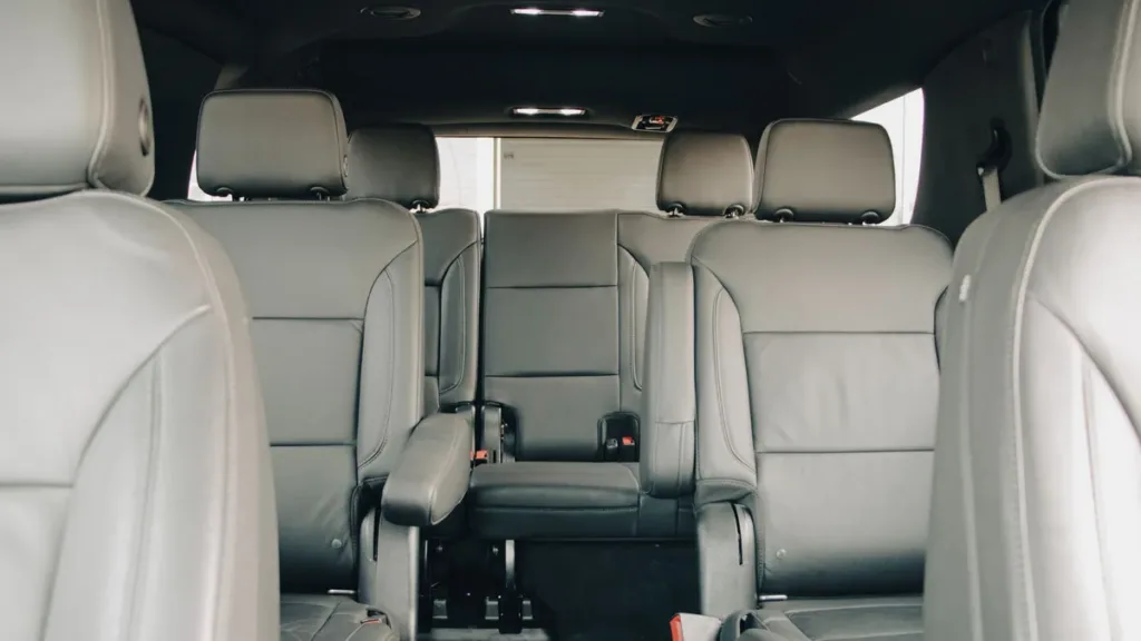 Rear cabin of a people carrier with grey leather captain's chairs and a third-row seat, viewed from the back