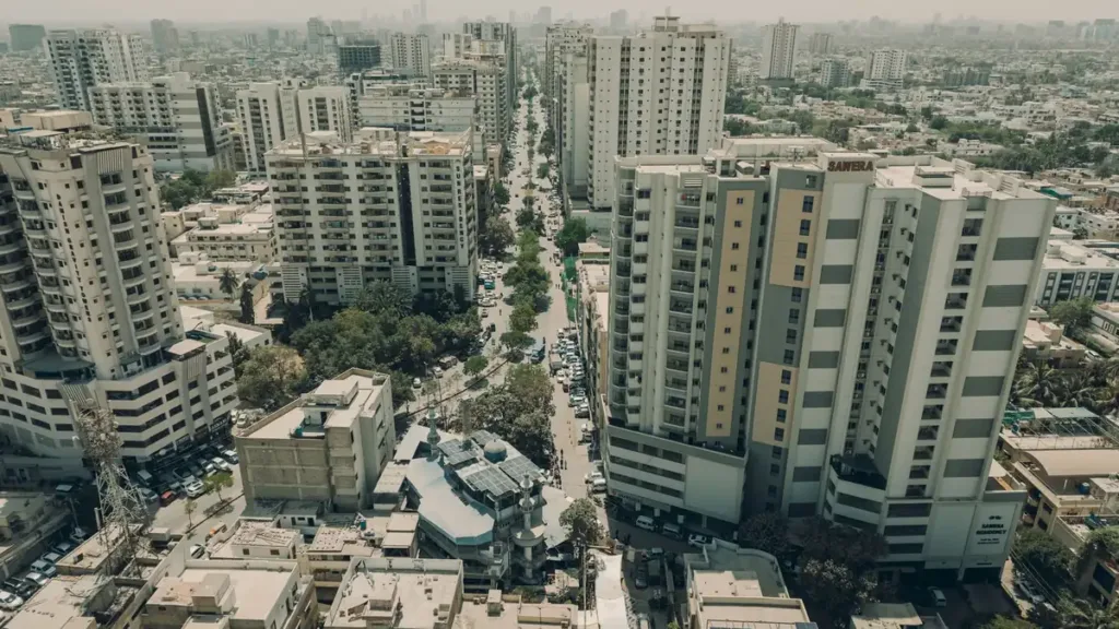 Aerial view of high-rise apartment towers along a tree-lined avenue in Karachi on a hazy day