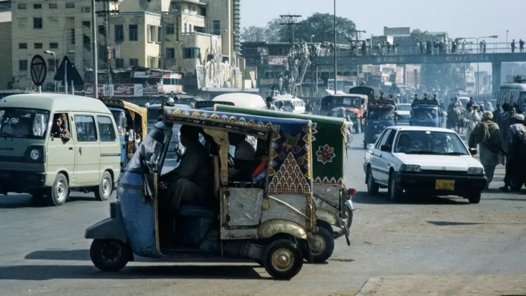 Auto rickshaw and cars on a city road in Pakistan, where most short-trip fares are agreed before departure