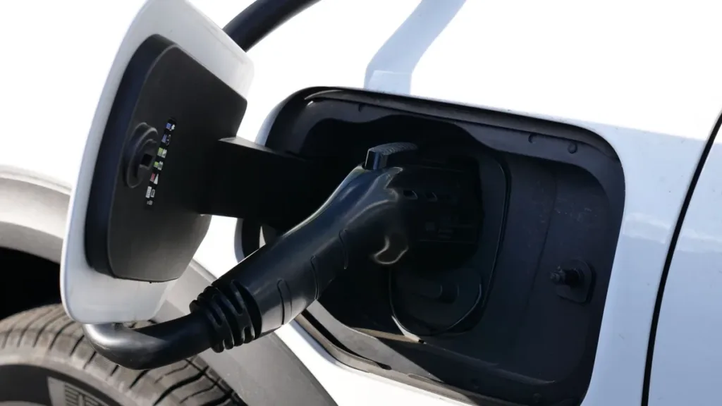 Close-up of a charging cable plugged into the open charging port of a white electric car
