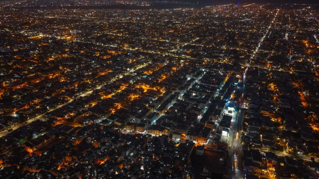 Aerial night view of Karachi with a dense grid of streets and buildings lit by orange streetlights