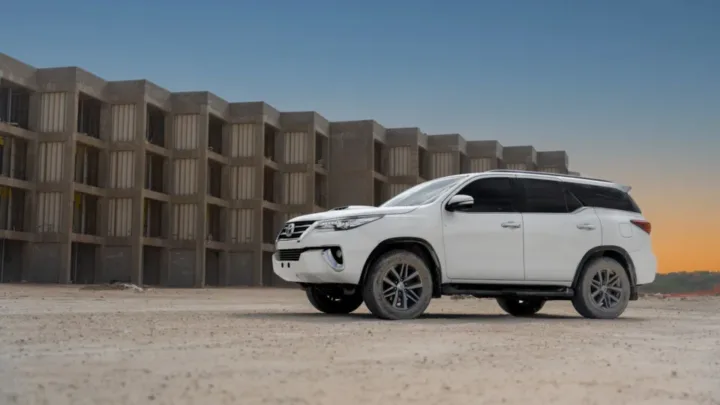 Toyota Fortuner, white SUV beside a concrete building at dusk