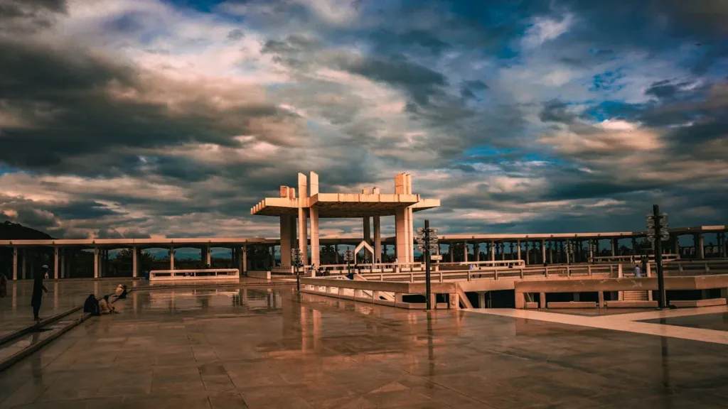 Wide stone plaza and white pavilion structure in Islamabad under a dramatic cloudy evening sky