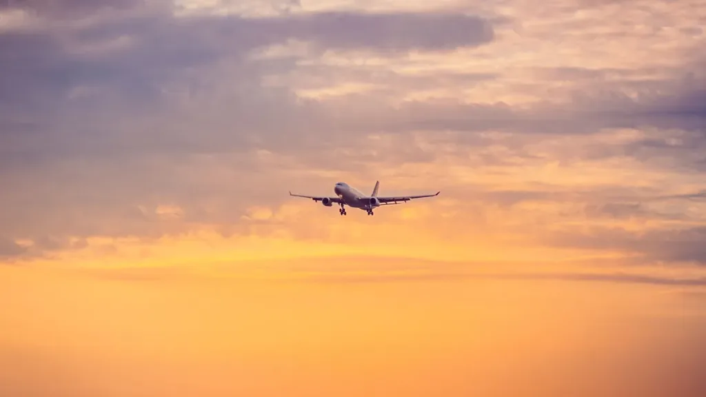 Passenger jet on approach against a golden sunset sky with soft layered clouds