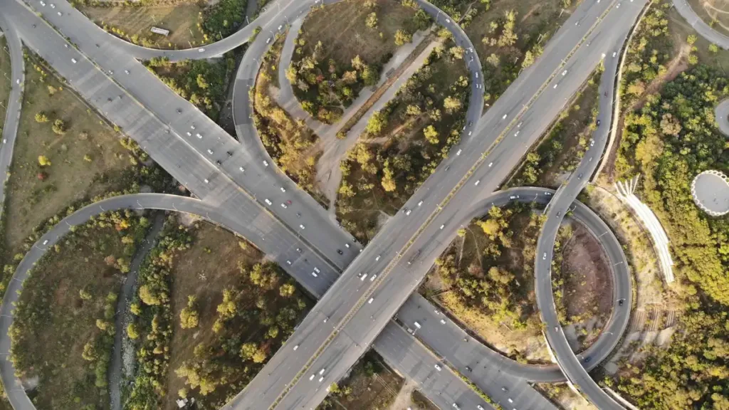 Aerial view of a multi-level highway interchange with looping ramps set among trees and green verges