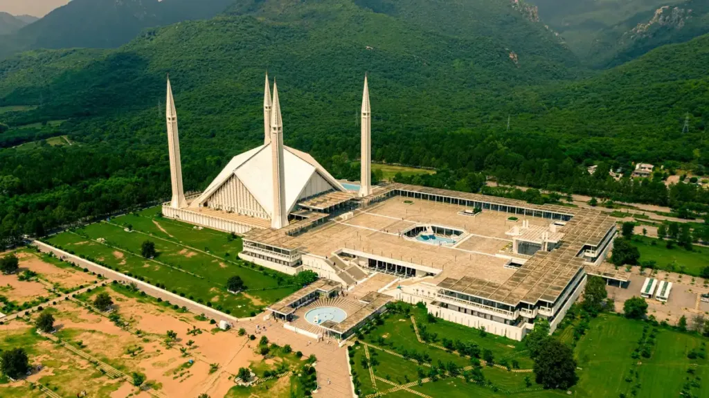 Aerial view of Faisal Mosque with its four minarets set against the green Margalla Hills in Islamabad