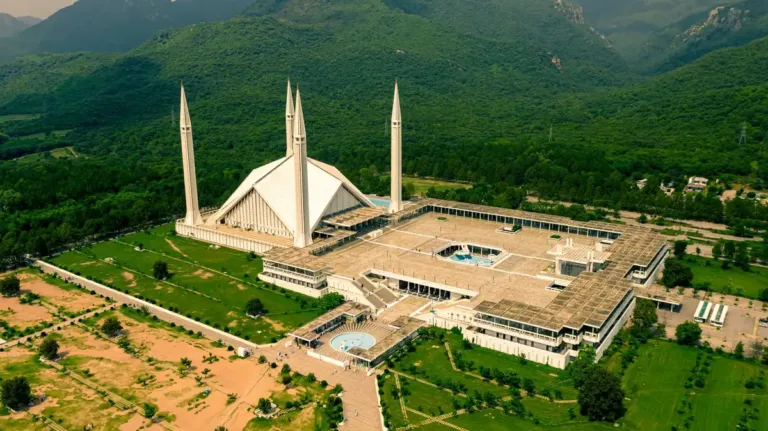 Aerial view of Faisal Mosque with its four minarets set against the green Margalla Hills in Islamabad