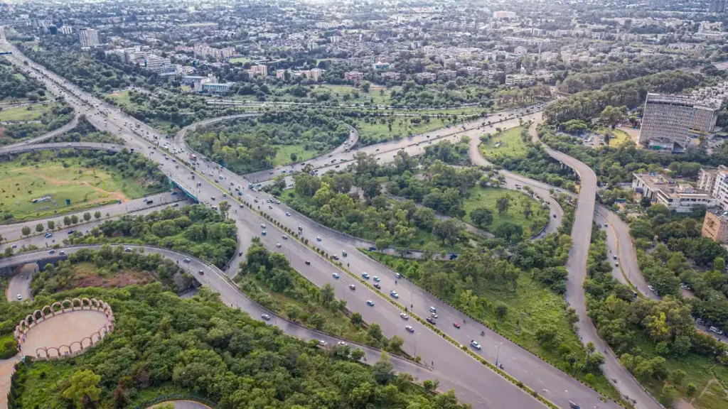 Aerial view of a multi-lane expressway interchange in Islamabad winding through green parkland and city blocks