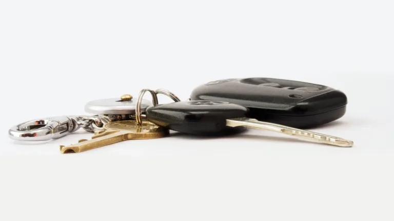 A car key fob and a bunch of house keys lying on a plain white surface, photographed close up