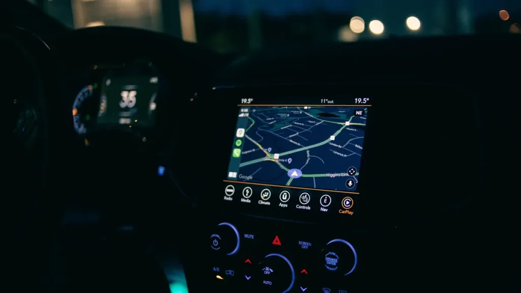 Car centre console at night with an illuminated navigation map screen showing the route ahead