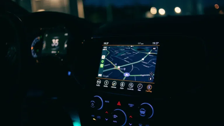 Car centre console at night with an illuminated navigation map screen showing the route ahead