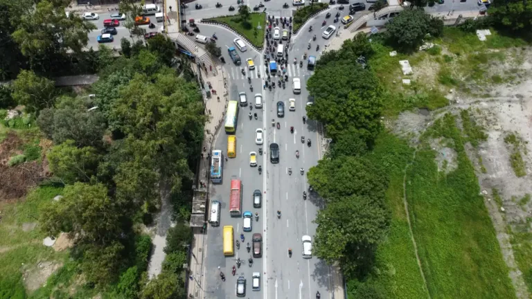Aerial view of a busy tree-lined city road carrying buses, cars and motorbikes during the daily commute