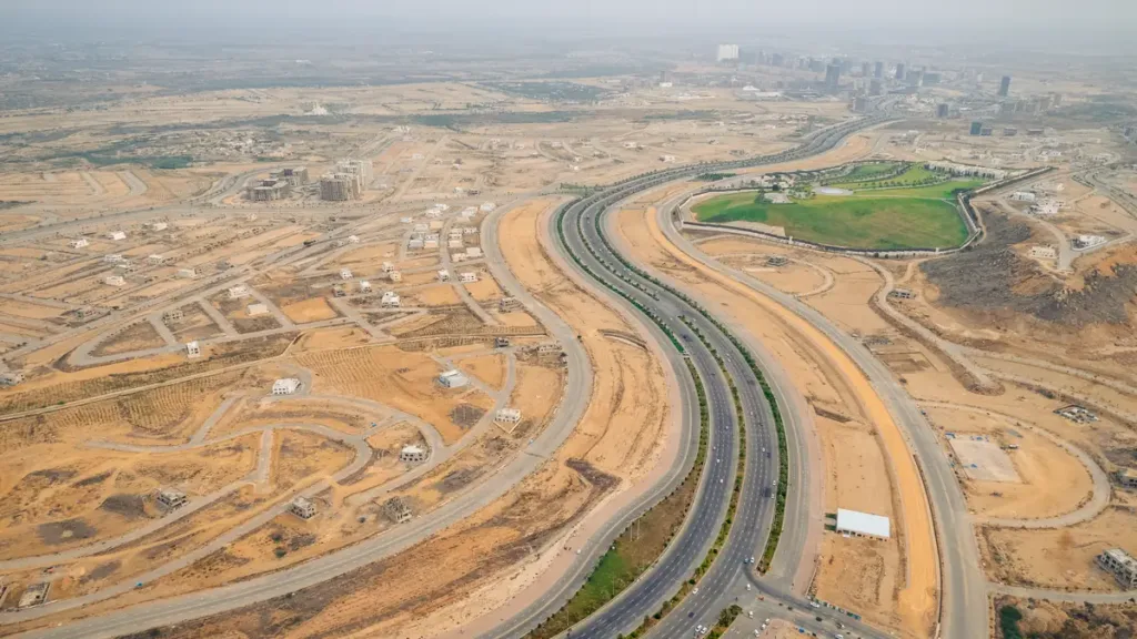 Aerial view of a multi-lane highway curving through dry land with new roads and construction plots on both sides
