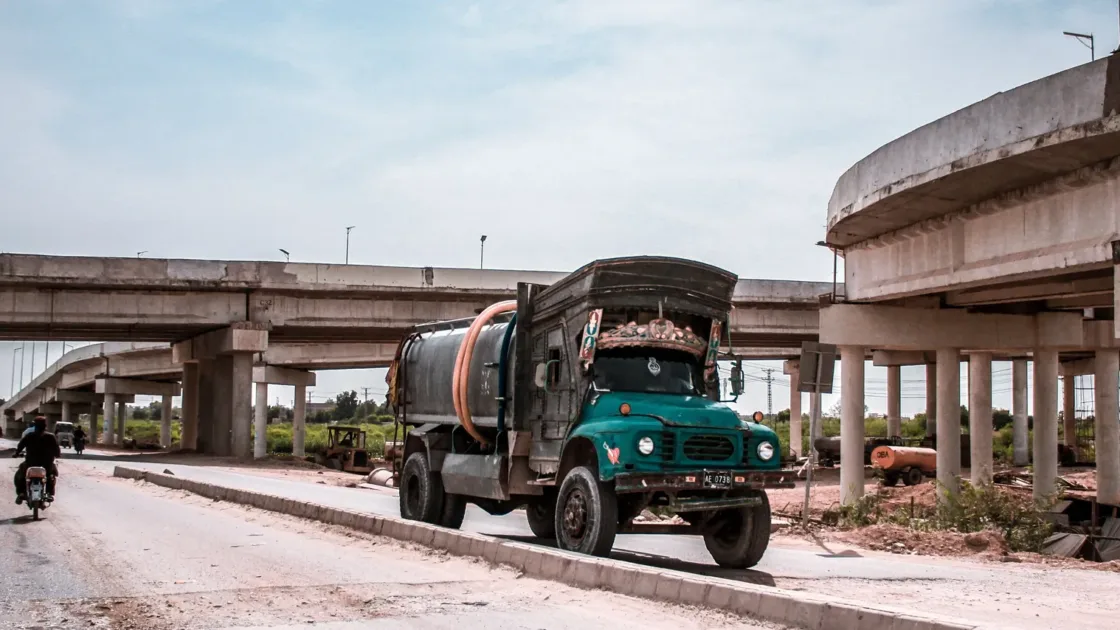 A tanker truck and motorbikes on a highway beside a flyover in Kotri, Sindh, across the Indus from Hyderabad