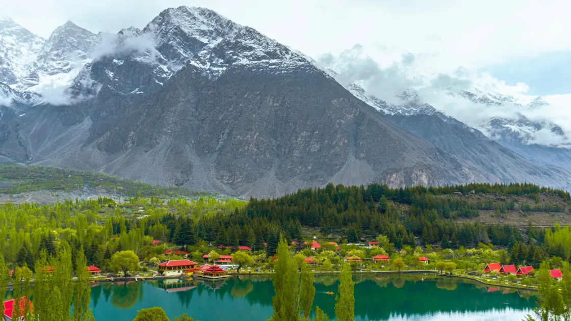 Shangrila Resort and its turquoise lake with red-roofed buildings near Skardu, below snow-capped mountains